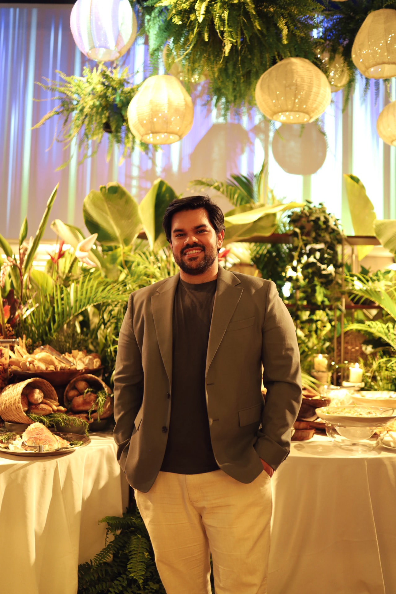 Carlos da CAZ em evento decorado com vegetação suspensa, lanternas e mesa de buffet